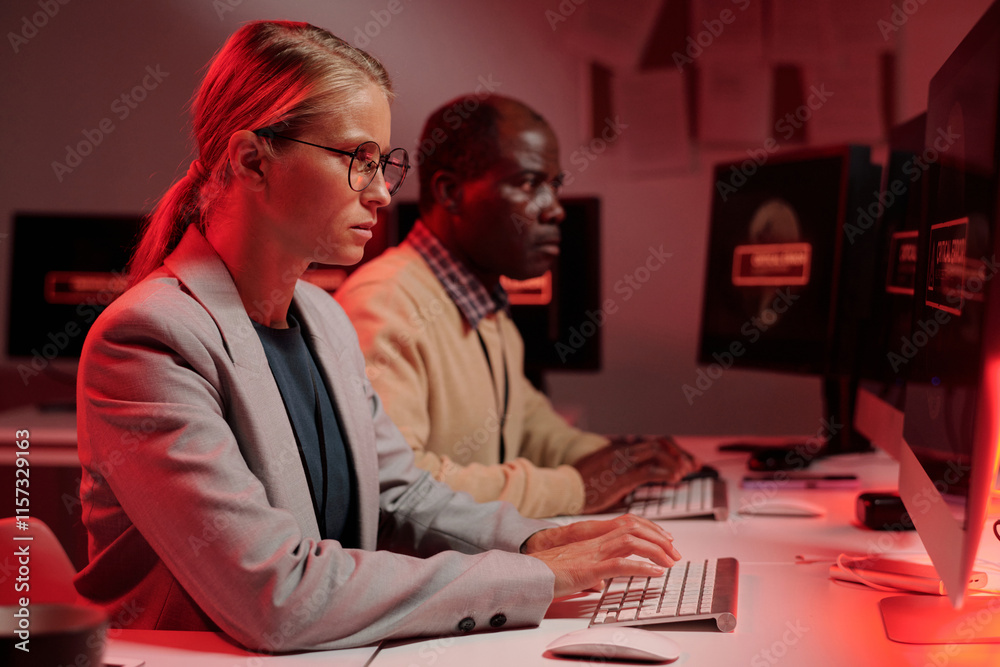 Aufkleber Young serious female security guard solving technical problem while sitting in front of computer screen and typing