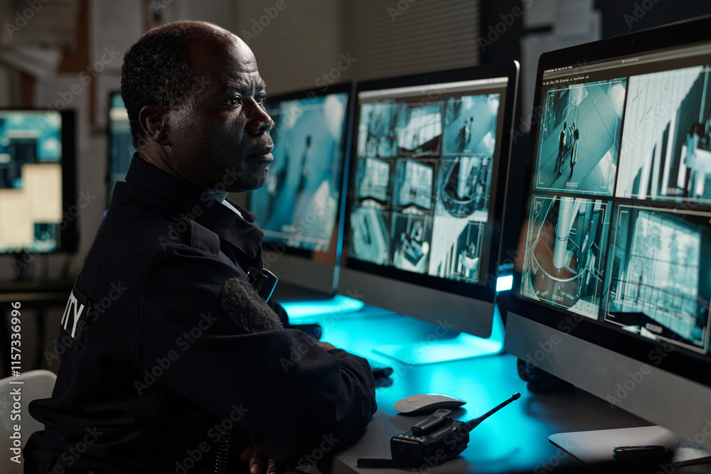 Poster mature male security guard concentrating on watching cctv video on desktop computer screen while sit