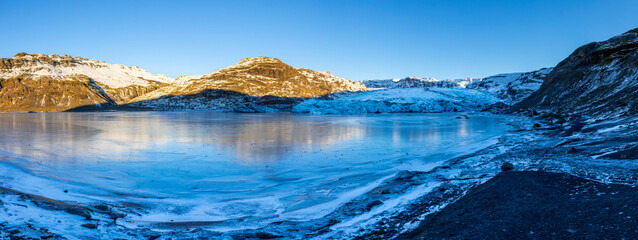 Panoramic view of Solheimajökull glacier in winter with frozen lake and moody winter light