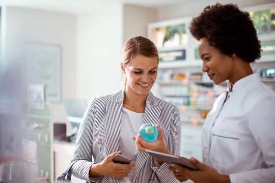 Pharmacist assisting woman with medication choice in pharmacy