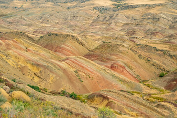 Stunning landscape of rolling hills with vibrant earth tones under a clear sky at midday