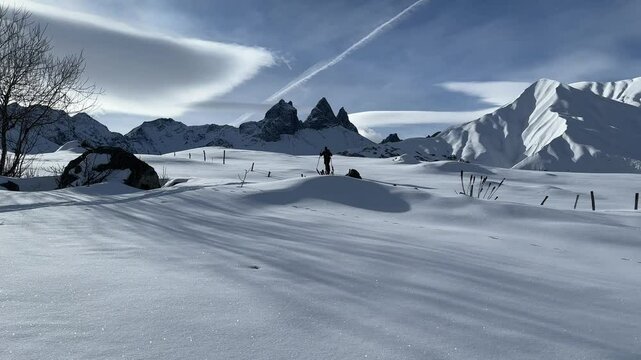 Man doing ski touring in front of the aiguilles d'arves mountains by a sunny day; ski mountaineering in winter in the french alps with fresh snow