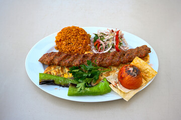 Grilled Turkish Adana, Urfa  Kebab with grilled vegetables, onion and rice on plate. Adana durum, Urfa durum .