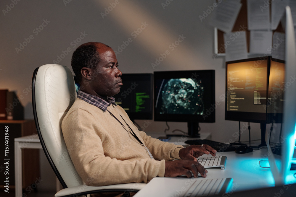 Poster Serious African American IT manager or programmer decoding data on desktop computer screen while sitting by workplace