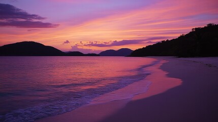 Tranquil tropical beach sunset with vibrant colors reflecting on calm waters and gentle waves enhancing the serene atmosphere.