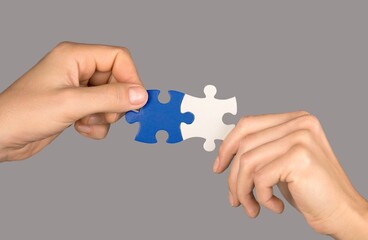 Man and woman hands holds jigsaw puzzle.