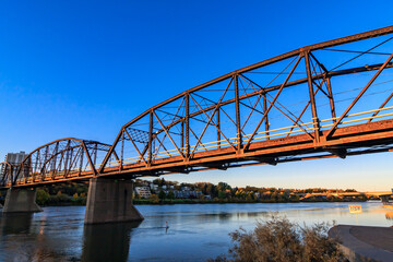 A bridge spans a river with a clear blue sky in the background