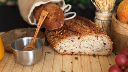 Rustic setup with seeded bread, grapes, pears, wheat stalks, metal bowl with salt ,wooden accents...