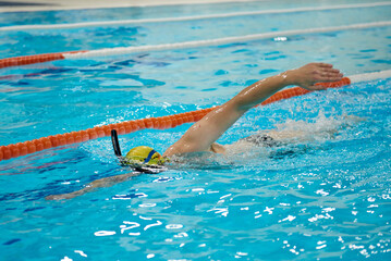 A man is crawling in a pool with a snorkel.