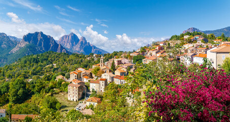 Naklejka premium Evisa, Corsica, a picturesque hillside village with red-roofed houses, vibrant flowers, and stunning mountain views.