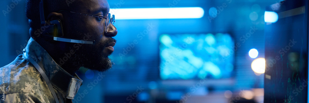 Aufkleber header of serious male military operator in headset, eyeglasses and camouflage uniform looking at co