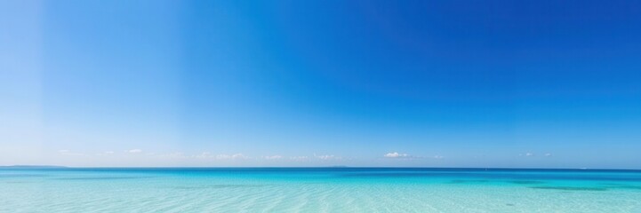 Fototapeta premium Stunning panoramic view of a serene turquoise ocean blending seamlessly into a clear blue sky with soft white clouds in a tranquil tropical paradise setting.