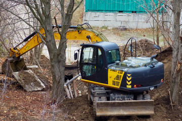 A backhoe loader lifting a concrete slab during the repair of a water pipeline, backhoe loader in...