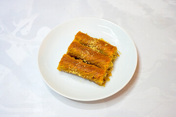 Pistachio kadayif on a plate. Turkish Dessert Kadayif with pistachio powder. Local name burma kadayif, antep fistikli, cevizli kadayif .