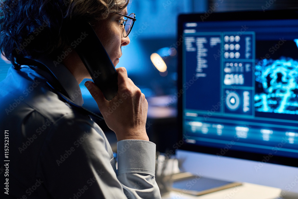 Aufkleber focus on mature woman in uniform holding phone receiver by ear and looking at computer screen while 