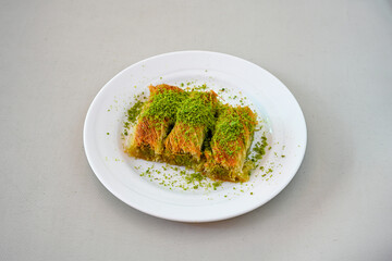 Pistachio kadayif on a plate. Turkish Dessert Kadayif with pistachio powder. Local name burma kadayif, antep fistikli, cevizli kadayif .