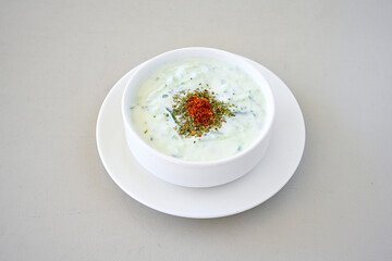 Tzatziki, cacik, or tarator is a traditional Turkish and Greek appetizer made from fresh yoghurt, cucumbers, spices and olive oil in a white plate. 
