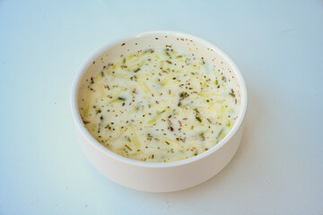 Tzatziki, cacik, or tarator is a traditional Turkish and Greek appetizer made from fresh yoghurt, cucumbers, spices and olive oil in a white plate. 