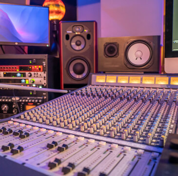 professional audio mixing console with studio monitors and equipment in the background, ideal for music production and sound engineering
