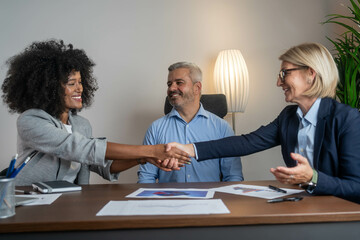 Cheerful business people shaking hands in the office. Finishing successful meeting. Business handshake and business people concept. Partnership, deal, agreement.