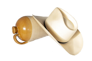 Isolated cowboy hat with empty old pottery jug resting on its side shows western casual living or dude ranch old west idea.