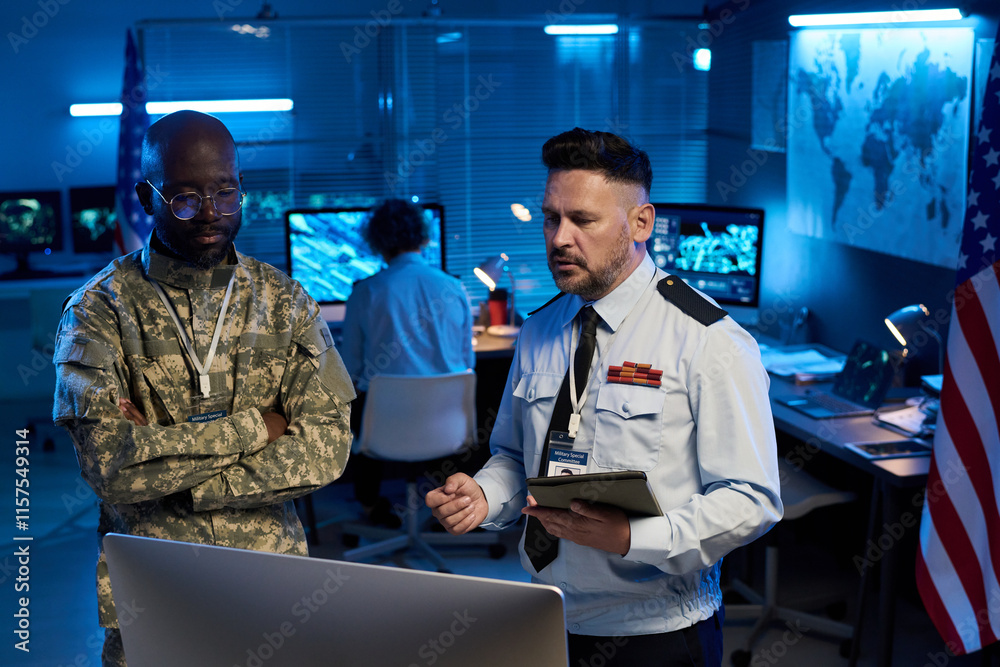 Aufkleber young and mature intercultural male military officers in uniform discussing data on computer screen 