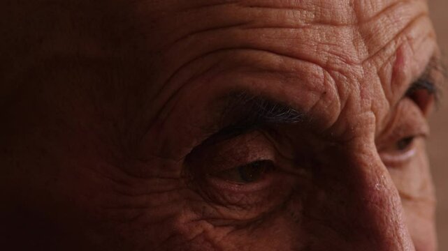 close up of caucasian elderly man eye 80 years old , sad look of pensioner , real old people