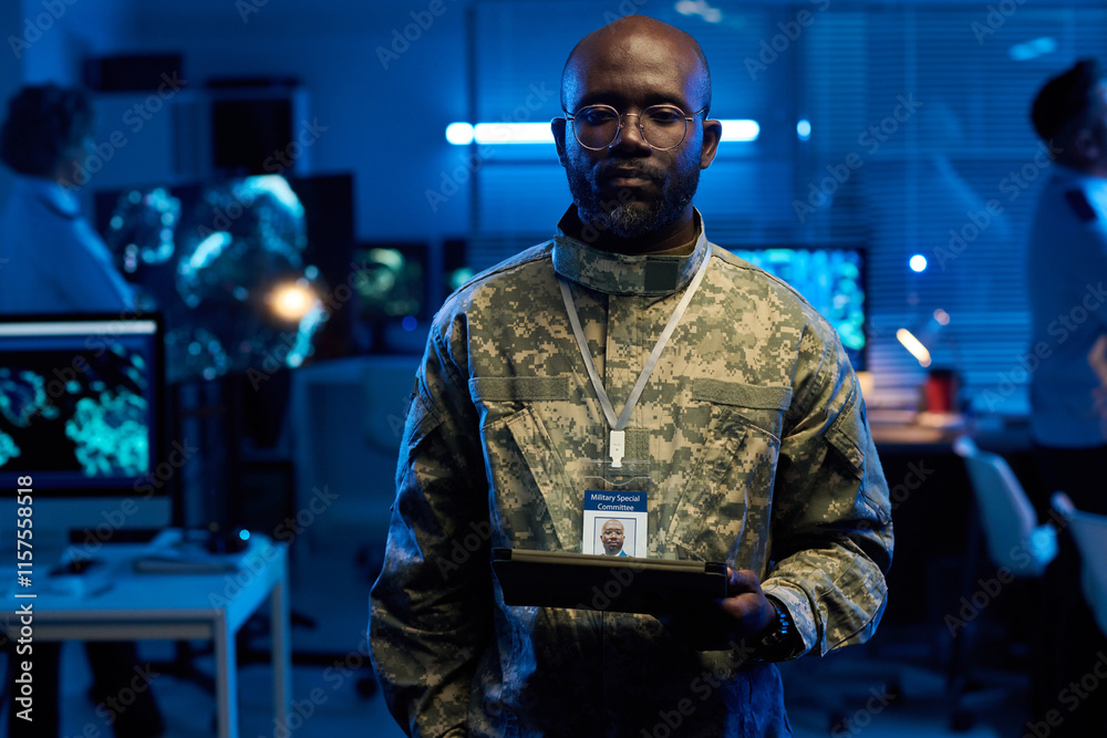 Aufkleber young serious african american man in camouflage uniform looking at tablet screen while working in m
