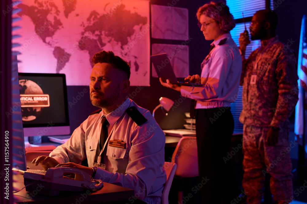 Aufkleber serious mature male officer sitting in front of desktop computer and looking at screen while typing 