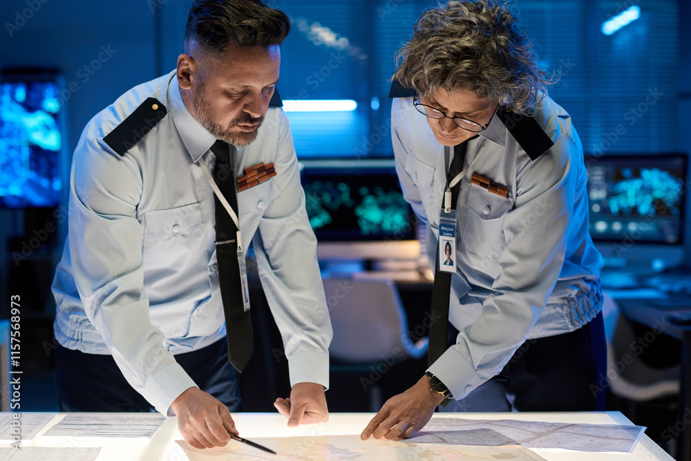 Aufkleber mature male and female military officers bending over table with paper documents while pointing at d