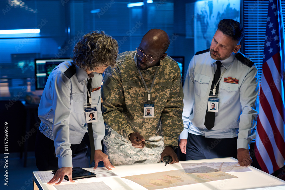 Leinwandbilder group of three intercultural workers of military command center discussing map or other documents by