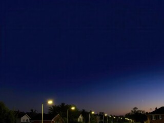 Fototapeta premium Serene Night Sky Over a Quiet Suburban Street Illuminated by Streetlights with a Hint of Dusk on the Horizon
