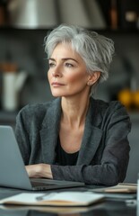 Senior woman working from home, thoughtful at kitchen desk