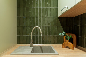 Textured sink paired with a beige faucet and glossy green tiles