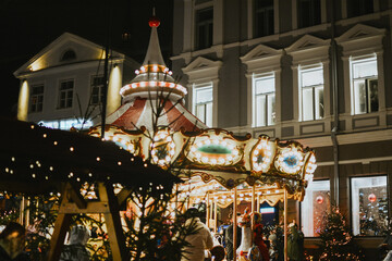 Colored carousel at christmas market at town hall of europe city decorated with lights at night