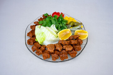 Cig kofte (raw meatball) with lettuce, tomato, pickle and lemon, hot Chee kofta. Turkish local raw food concept.Table scene of assorted take out or delivery foods. Doritoslu duble cig kofte durum.