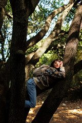 girl having fun in nature. cheerful young girl. the girl hangs on a tree and smiles.