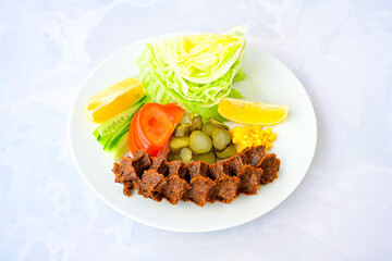 Cig kofte (raw meatball) with lettuce, tomato, pickle and lemon, hot Chee kofta. Turkish local raw food concept.Table scene of assorted take out or delivery foods. Doritoslu duble cig kofte durum.