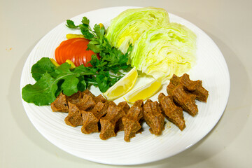Cig kofte (raw meatball) with lettuce, tomato, pickle and lemon, hot Chee kofta. Turkish local raw food concept.Table scene of assorted take out or delivery foods. Doritoslu duble cig kofte durum.