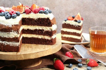 Delicious chocolate sponge cake with berries served on wooden table