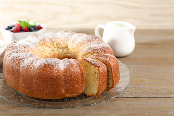 Freshly baked sponge cake, milk and berries on wooden table, closeup