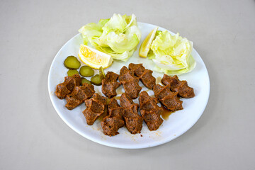 Cig kofte (raw meatball) with lettuce, tomato, pickle and lemon, hot Chee kofta. Turkish local raw food concept.Table scene of assorted take out or delivery foods. Doritoslu duble cig kofte durum.