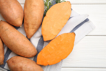 Fresh raw sweet potatoes and rosemary on white wooden table, top view