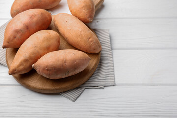 Fresh raw sweet potatoes on white wooden table, above view. Space for text