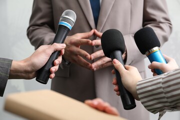 Group of journalists interviewing businessman indoors, closeup