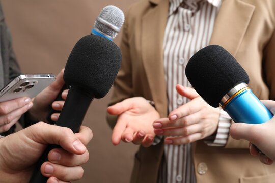 Group of journalists interviewing businesswoman on beige background, closeup