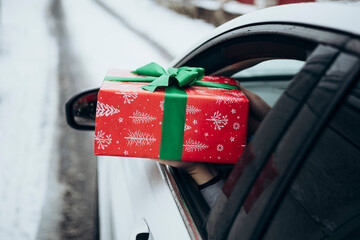 Hand Holds a Festive Gift from a Car Window in Winter Scene