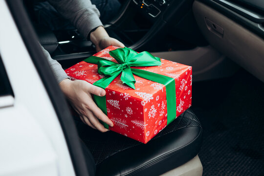 Hands delivering festive gift box in car interior - Powered by Adobe