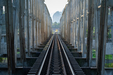 Close-up of railway tracks running through a steel bridge, showcasing a dramatic linear perspective and industrial design.
