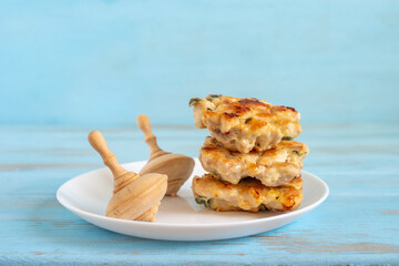 Chicken latkes or minced cutlets for Jewish holiday Hanukkah on ceramic plate over blue wooden background.
